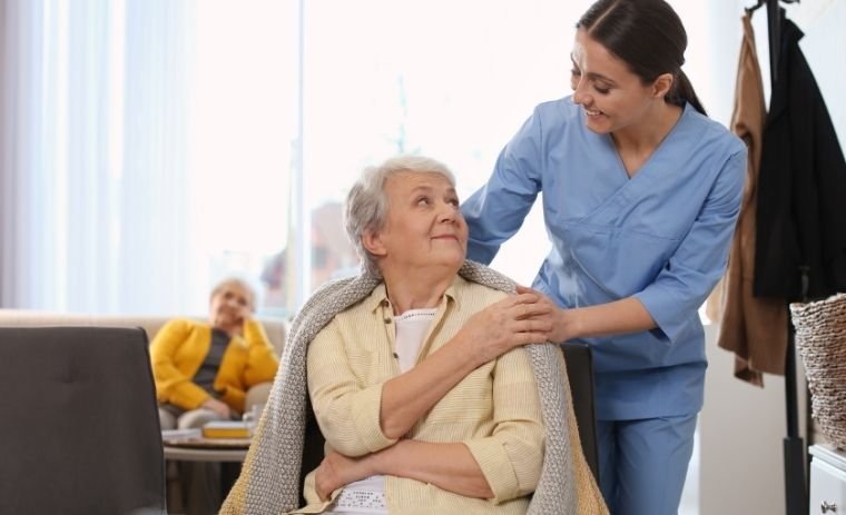 A smiling caregiver helping an elderly woman with a blanket at home, showing warmth and comfort - home care in Ohio for seniors
