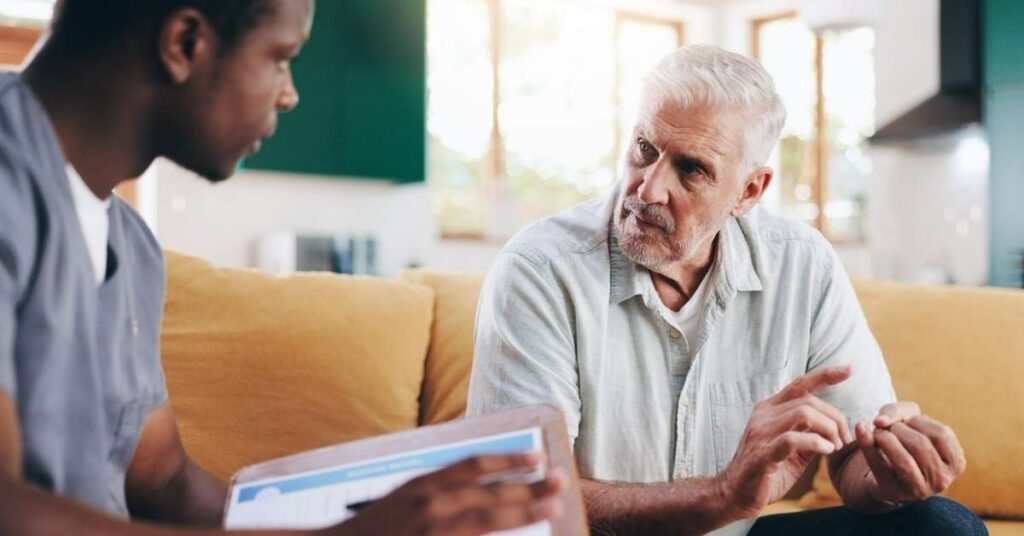 Professional caregiver discussing daily care needs with an elderly man at home, highlighting common challenges for family caregivers and supportive home care guidance.