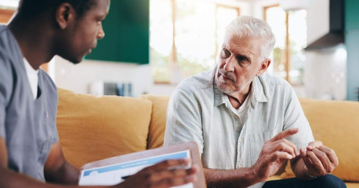 Professional caregiver discussing daily care needs with an elderly man at home, highlighting common challenges for family caregivers and supportive home care guidance.