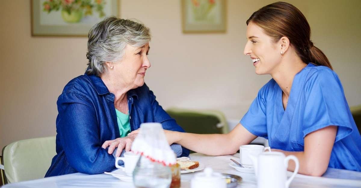 Companionship care caregiver providing emotional support and friendly conversation to an elderly woman at home in Ohio